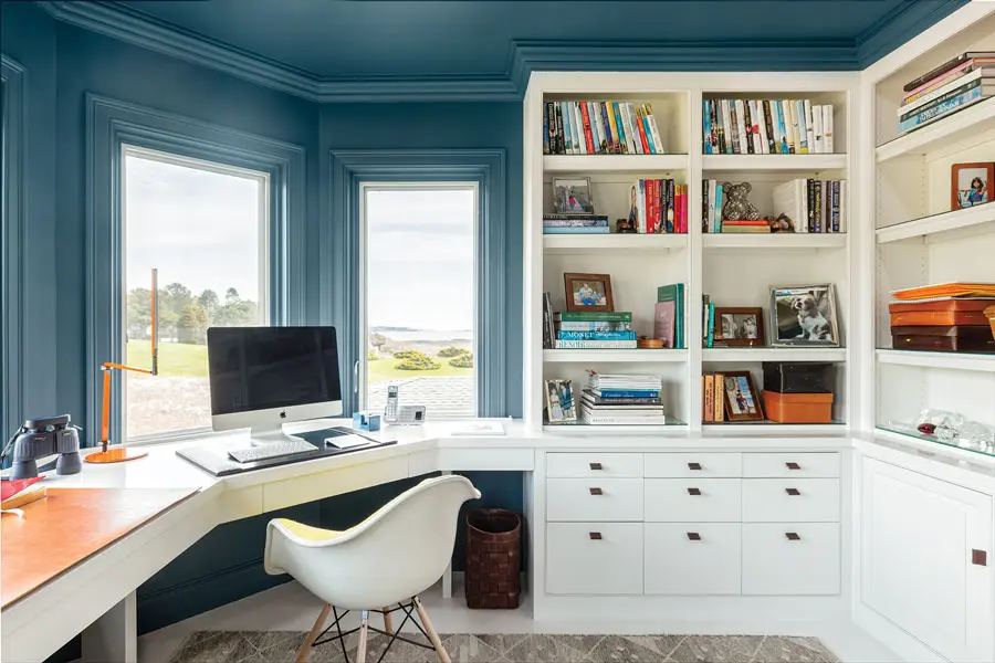 Deep teal on the walls, woodwork, and ceiling in the office play up the coastal setting.