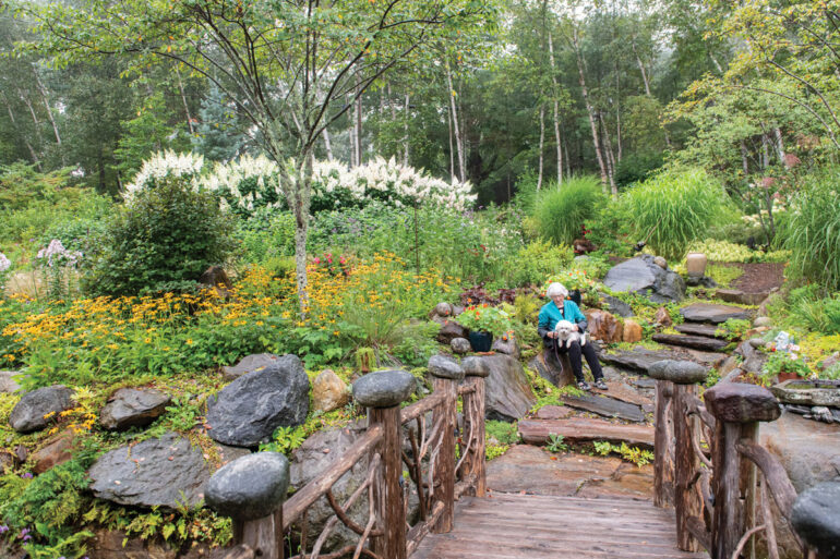 A cedar bridge studded with river stones leads from Ellen Shibles’s front door to her garden, where echinacea and rudbeckia bloom above a retaining wall by Mount Vernon’s Scott Horne Construction.