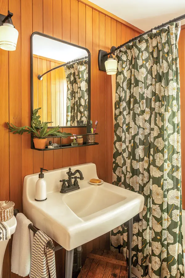 In the full bath, Millar installed sconces from Lowe’s with hand-painted glass shades from Schoolhouse, which also makes the shower curtain.