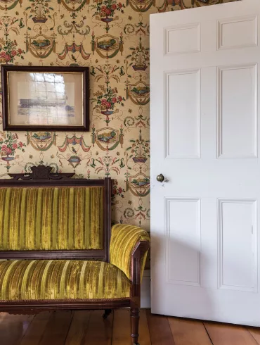 A Victorian-era settee sits beneath a circa-1860 photograph of a Grand Trunk Railroad steam locomotive built by the Portland Company in Harpswell's Captain Johnson H. Stover Jr. House