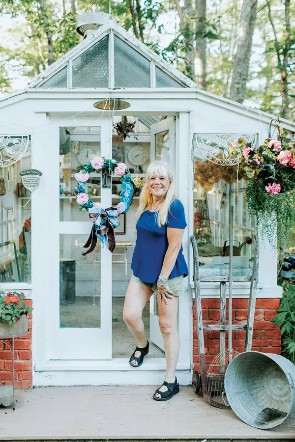 Pam Allen steps out of the greenhouse that Eric built with department-store glass shelving and discarded windows