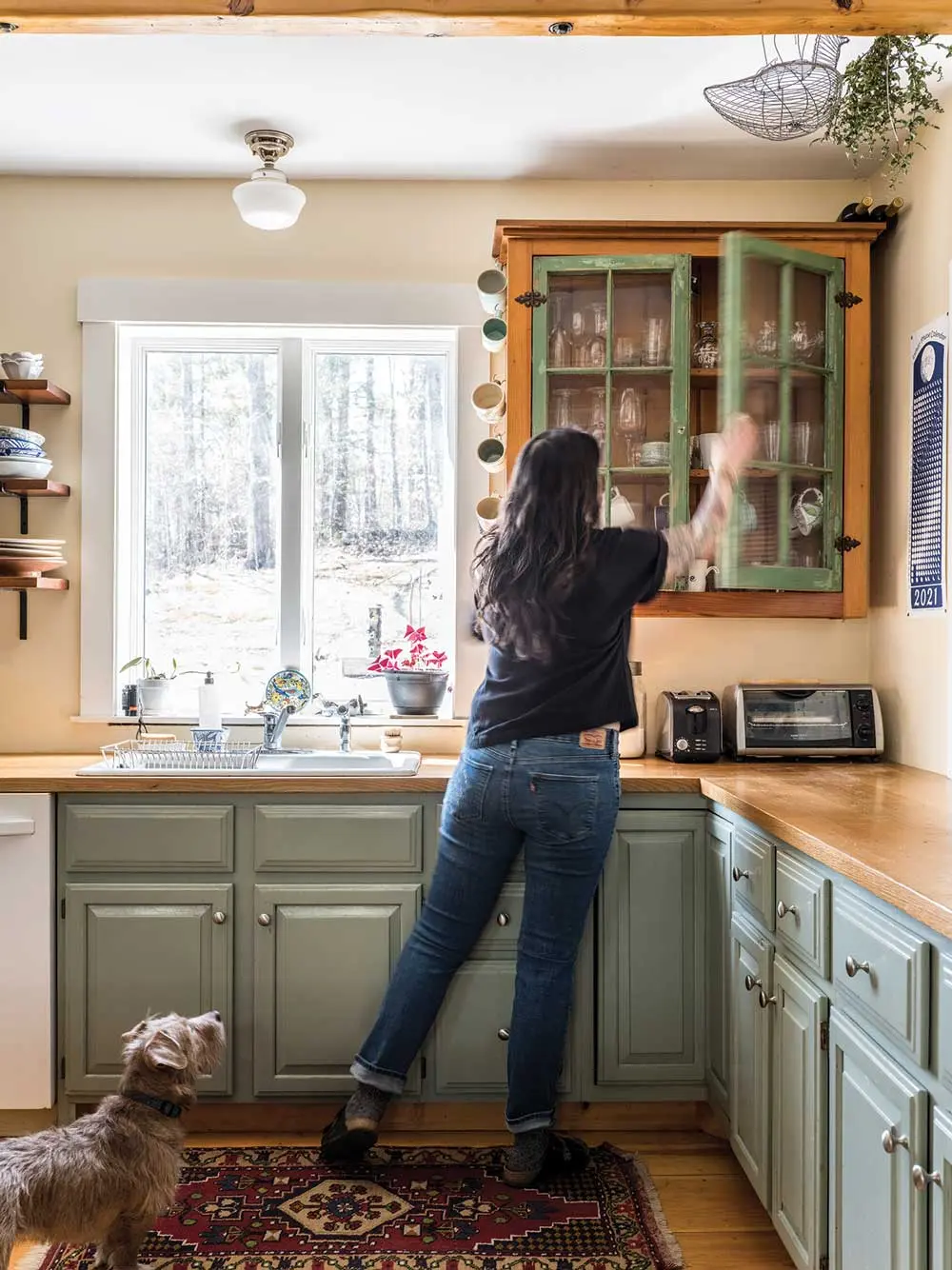 This Schoolhouse Rocks! Juliana McClain reaches into a cabinet that Joel built for her as a gift using windows from a cabin he helped tear down on Pemaquid Point.