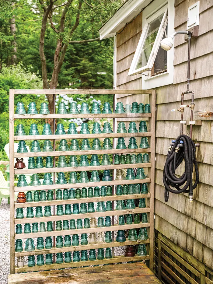 An outdoor shower screen comprising vintage glass electrical insulators.