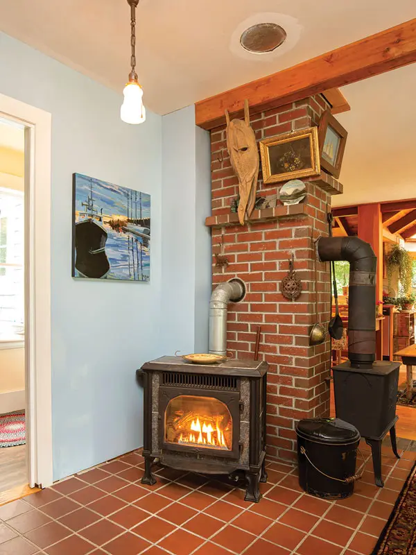 A gas stove (left) supplies most of the home’s heat, with an adjacent woodstove (right) providing backup heat