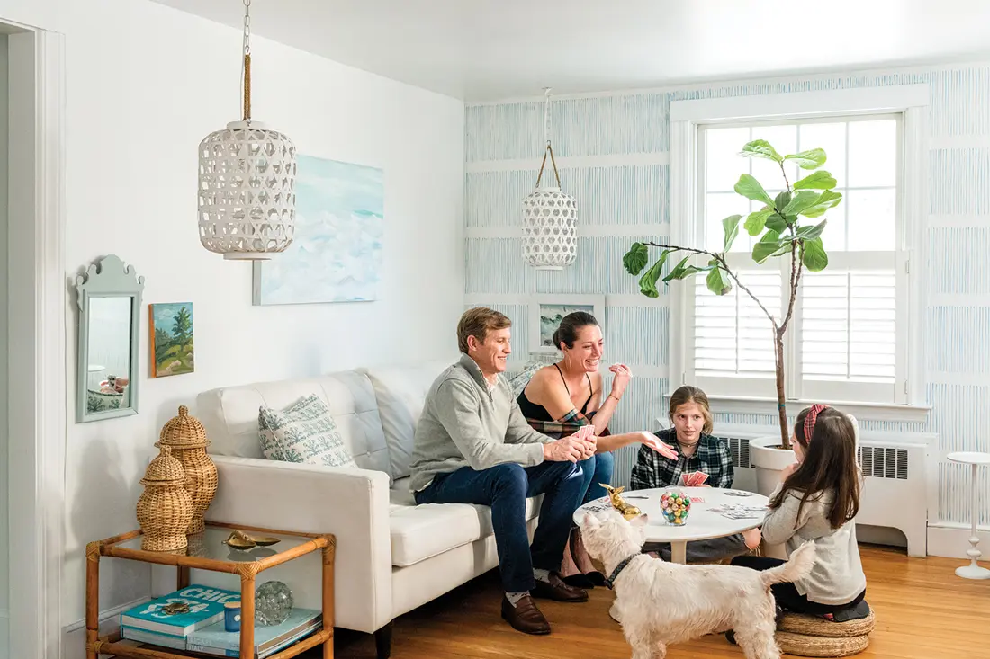 Marty, Erin, Reagan, and Wynnie hang out next to a pale-blue mural designed, Erin Gajan in the living room