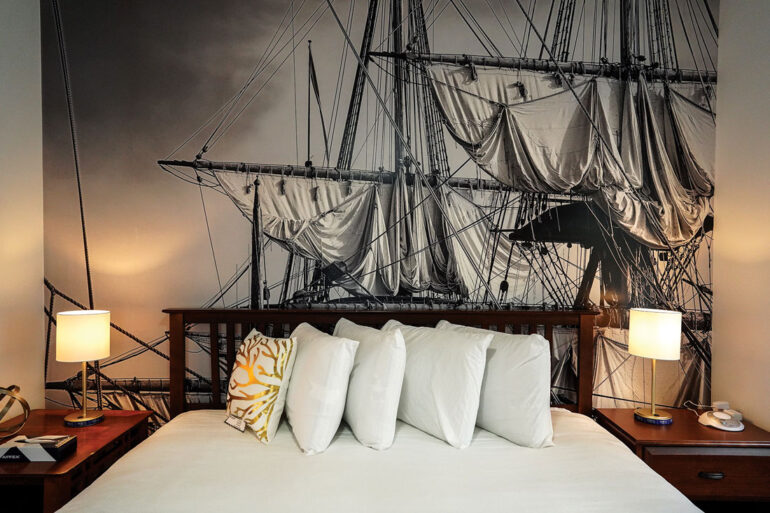 a floor-to-ceiling photo of a tall ship backdrops the headboards at Queen Anne's Revenge in Bar Harbor, Maine