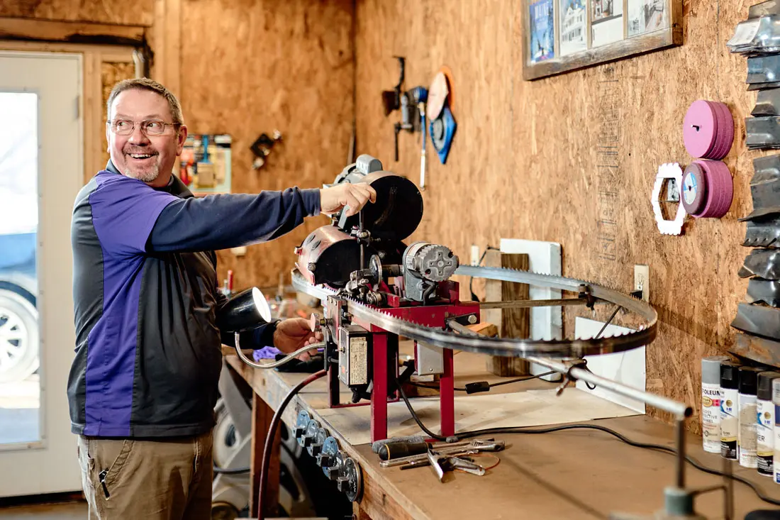 Gus Fillebrown sharpening a saw blade at Complete Sharpening Service in Bridgton, Maine
