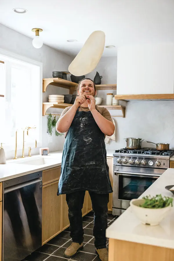Joe Camp tossing pizza dough in the Maine kitchen he shares with wife Kristen Camp