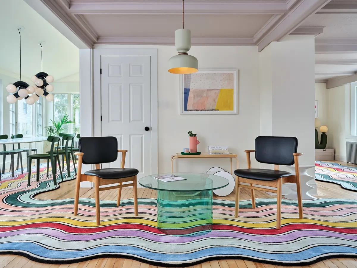 MHSpring2021_prof1 In the sitting room of Kennebunk’s Pieces Homes Airbnb, lavender-gray Backdrop ceiling paint, art by Ashley Peifer, and a glass-and-acrylic Pieces table speak to the shades in the company’s signature rainbow rug.