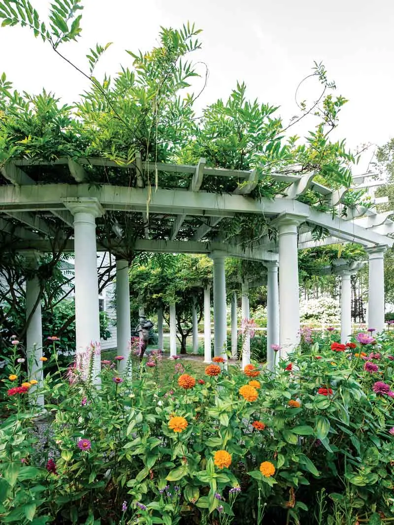 Scores of Colorful Glass Orbs Lend Continuity to This Harpswell Garden Wisteria spills from a trellis fronted with dahlias at the entry to one of the guesthouses