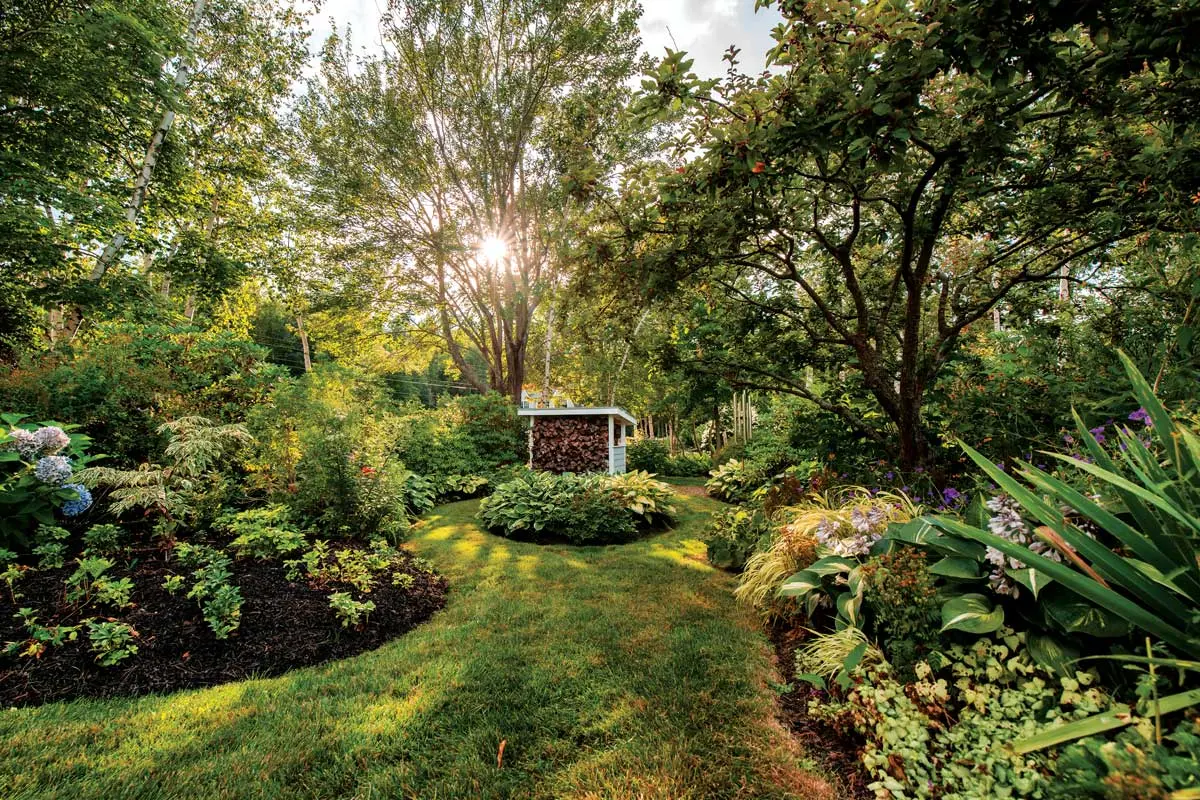 Scores of Colorful Glass Orbs Lend Continuity to This Harpswell Garden An old apple tree shades a memory garden at right.