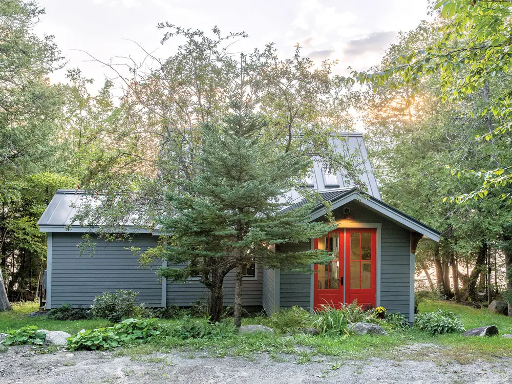 Rangeley Building & Remodeling added a mudroom with tomato-red doors inspired by a Rejuvenation sconce