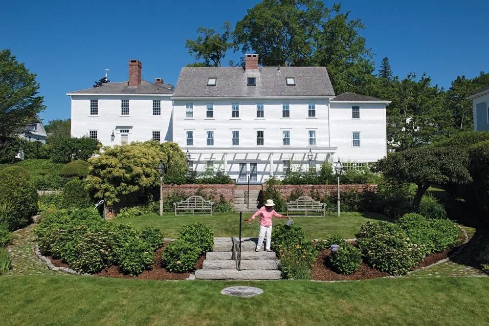 Leila sprinkles water on the hydrangeas, peonies, and other perennials that define and soften a terrace’s edges in the sloping “secret garden.”