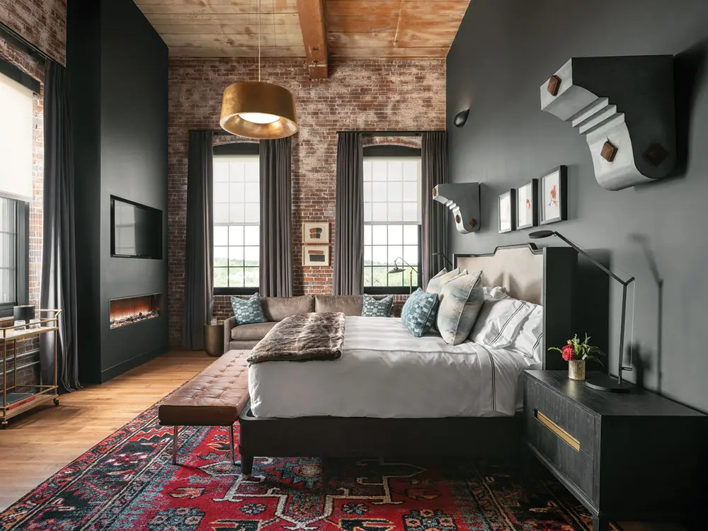 A gilded pendant juxtaposes with aged brick and wood in a guest room at the Lincoln Hotel in Biddeford Maine