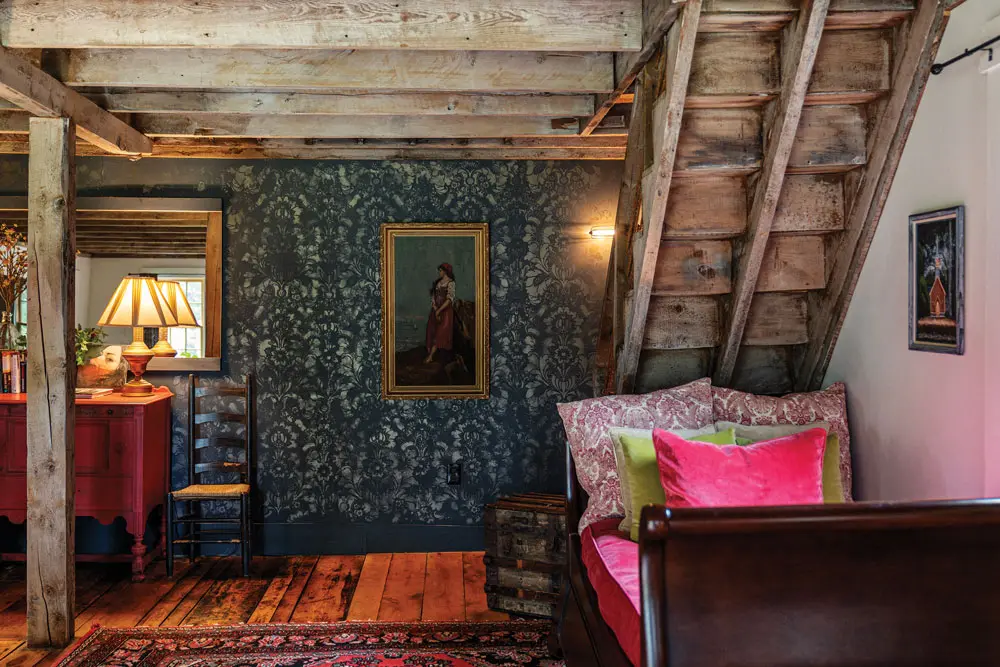 In her revamped Dover-Foxcroft barn, Brenda Schultz layered an oil painting from Brunswick’s Cabot Mill Antiques on a stenciled wall and toile and velvet pillows on a sleigh daybed.