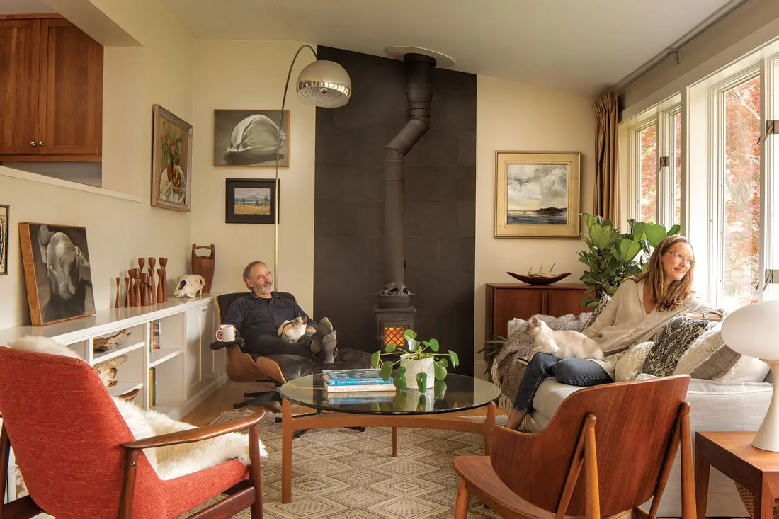 In the living room, Neil and Siamese cat Zahra relax on an Eames lounge chair beneath an Arco lamp by Pier Giacomo and Achille Castiglioni, while Stacey and Siamese Sybil perch on a sofa accented with Marimekko pillows.