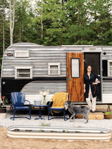 Katrina Kelley standing in the doorway of her vintage-camper-turned-mobile-boutique for her business, Amphitrite Linens