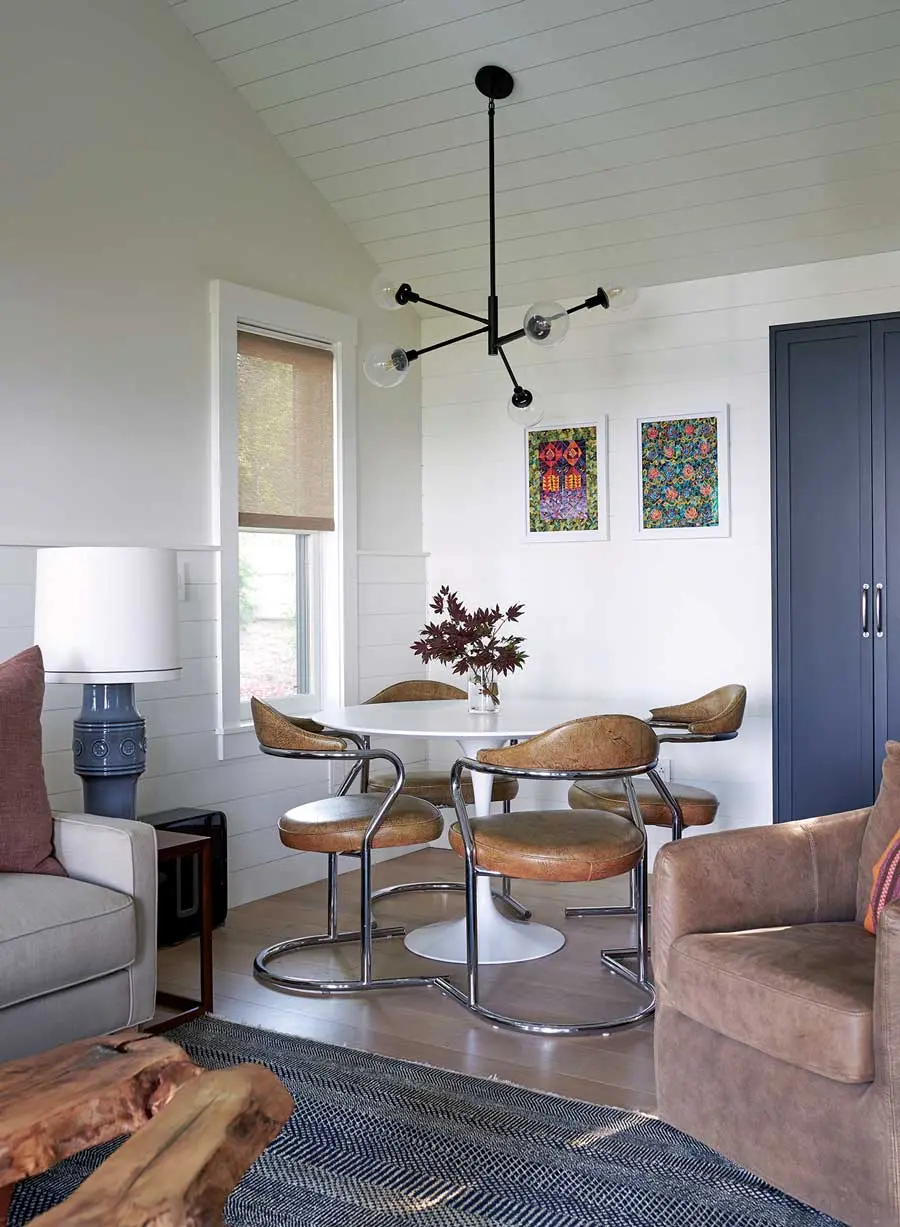 Works by Cape Elizabeth’s Missy Dunaway crown a Saarinen table surrounded with vintage leather chairs in a guesthouse dining area.