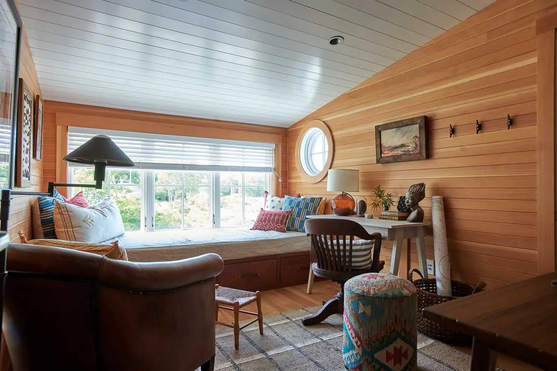the fir-paneled, third- floor office/guest room incorporates a custom walnut daybed, a vintage French armchair, an antique desk chair and bust