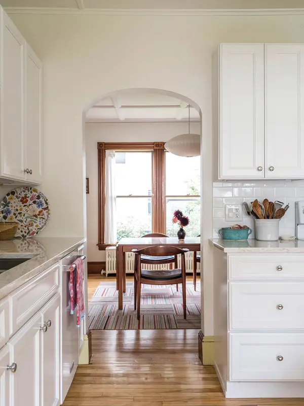 Despite being sequestered at the north end of the house, the kitchen is bright, thanks to a large window here and in the dining room beyond, and new snowy cabinets, countertops, and subway tile.