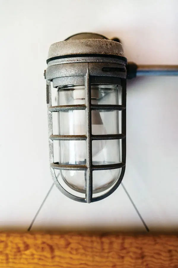 19th-century caged lights, steel-cleat handles on a steep, polished-wood rear staircase, and a stainless-steel shower from a submarine.
