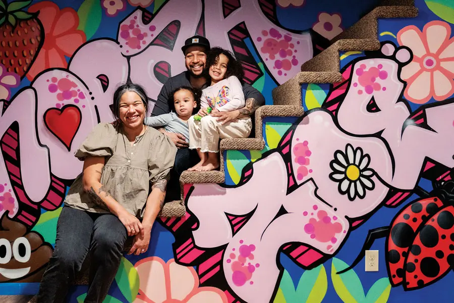 Rachel Gloria Adams, Ryan Adams, and their daughters with their staircase graffiti