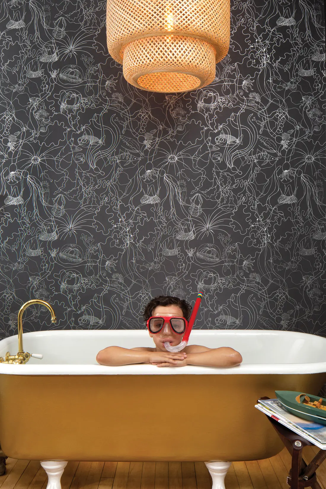 kid in bathtub in front of wallpapered wall