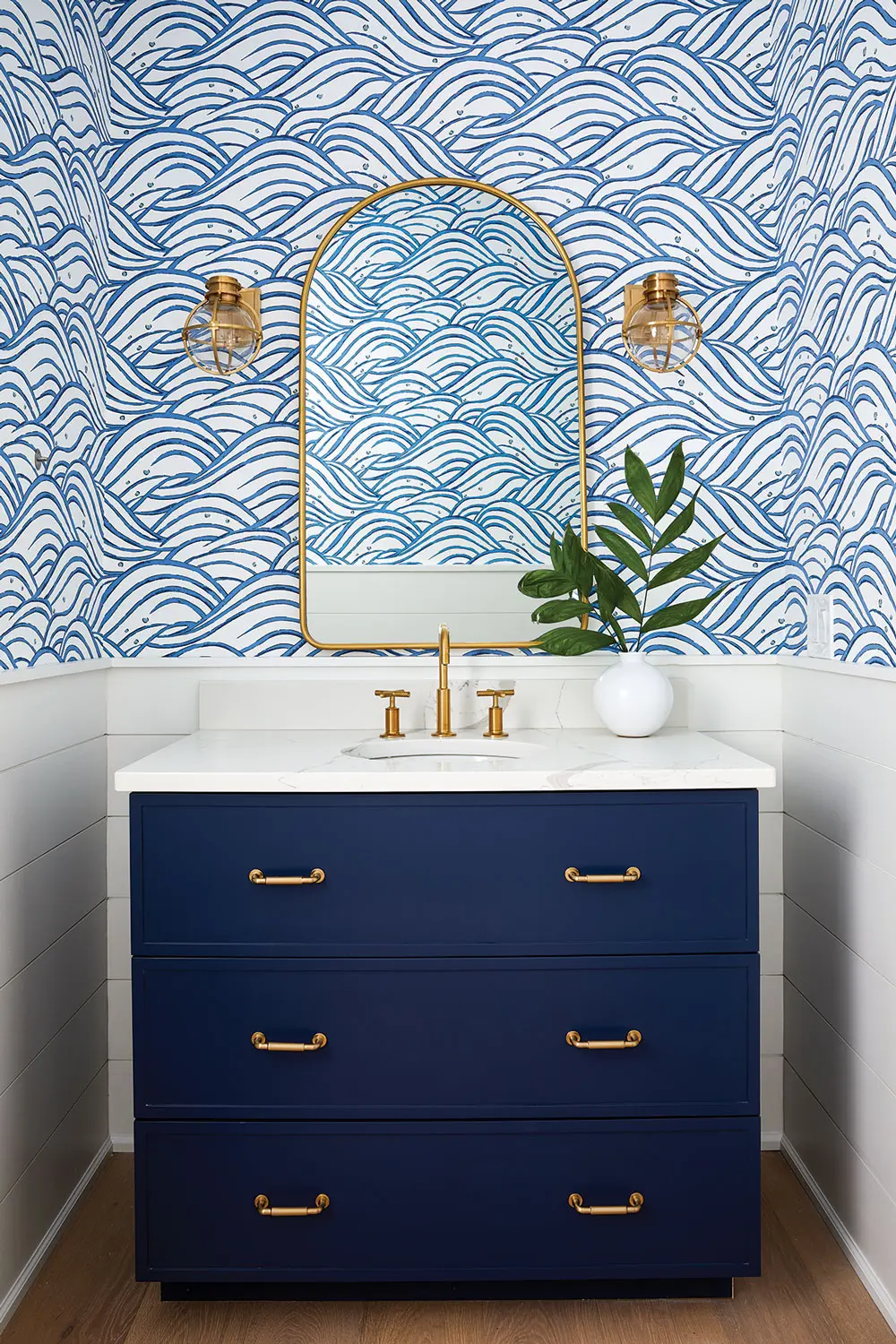 Thibaut’s stylized wave print, installed over shiplap, softens awkward angles in a Raymond lake-house bath designed by Fiore Home’s Vanessa Helmick.