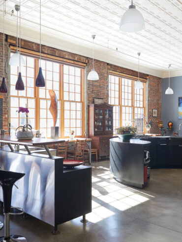 The kitchen in Amy Rees and Robert Lash’s 1887 Gardiner schoolhouse-turned-home features an original brick wall, tin ceiling, and blackboards — now forming an island top