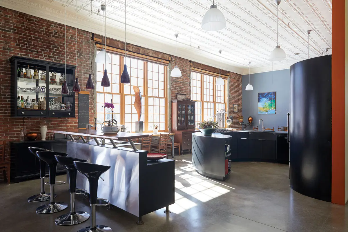 The kitchen in Amy Rees and Robert Lash’s 1887 Gardiner schoolhouse-turned-home features an original brick wall, tin ceiling, and blackboards — now forming an island top