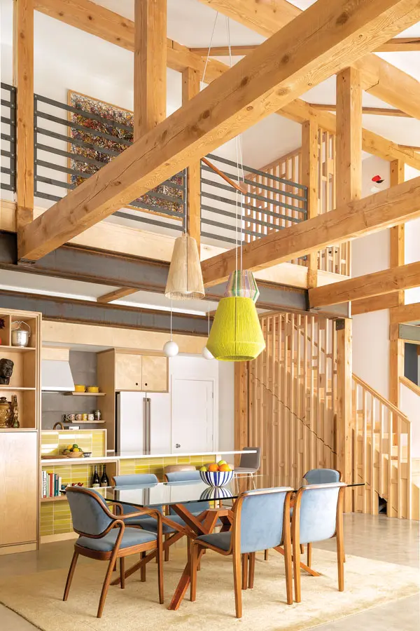 In the kitchen/dining area, oak Knoll chairs, a chartreuse wool pendant, and matching Heath Ceramics tile riff on the tones in steel beams and wooden elements