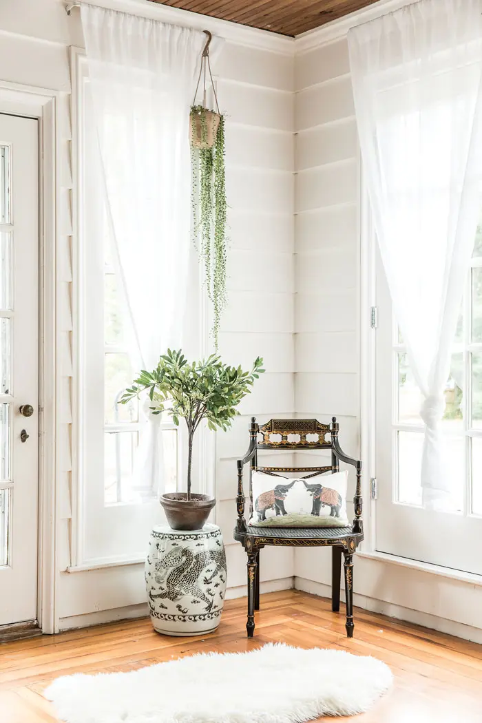 A 1920s-era English Regency chair from Pillars, topped with a John Robshaw pillow, anchors a porch corner.