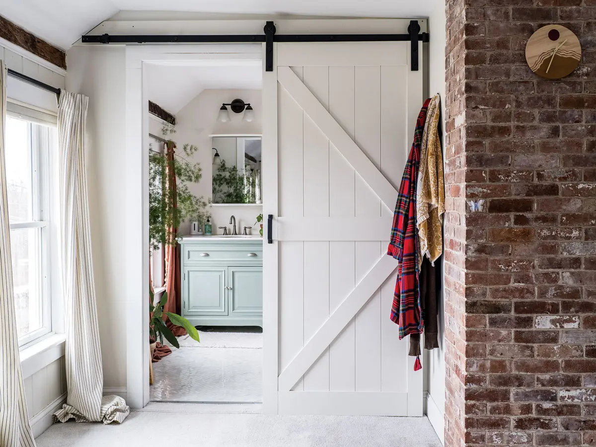 A barn door opens to a primary bath that was already updated and bright. “I start my dahlias there in early spring because it gets the best light,” Watka says.