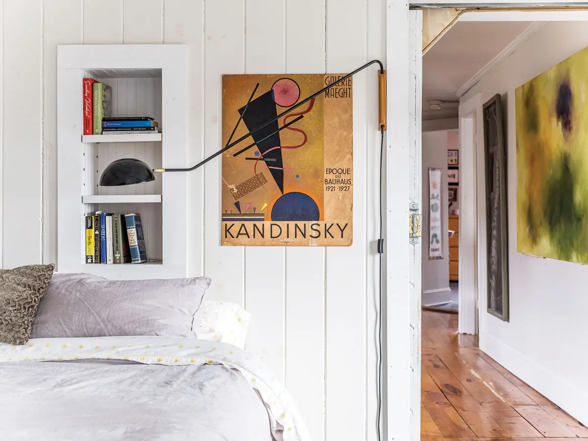In the primary bedroom, a CB2 sconce reiterates the shapes in a favorite poster from the Brimfield flea market.
