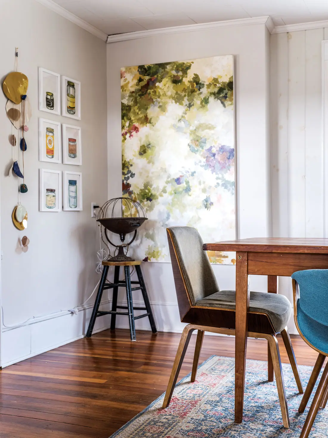 A hanging mica sculpture and botanical painting by Watka bookend framed works by Zoe Dieffenbach in the dining room.