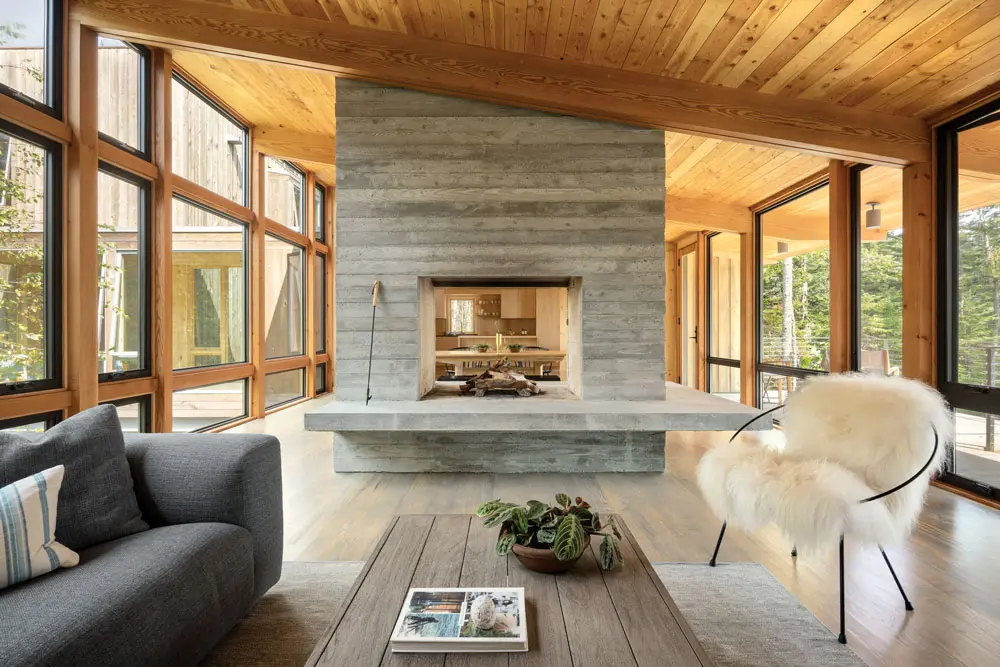 In the three-season porch, a double-sided, board-formed concrete fireplace divides the living and dining areas