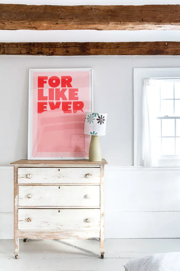 a silkscreened print rests atop a vintage bureau in the master bedroom