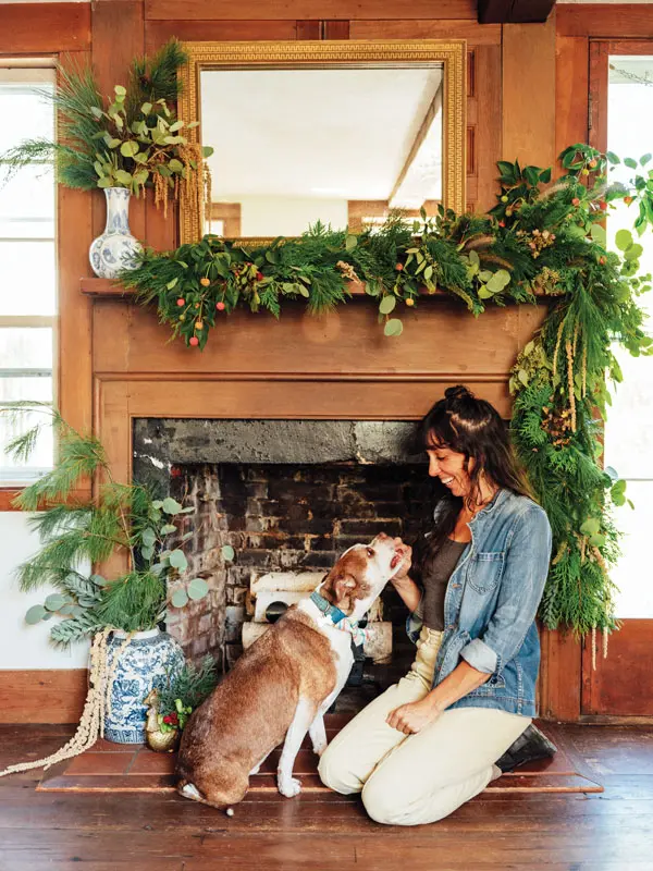 garden designer Abigail Pratt, of Star Gardens, and her pup in front of the evergreen garland on the mantel in her 1800s Portland Federal 