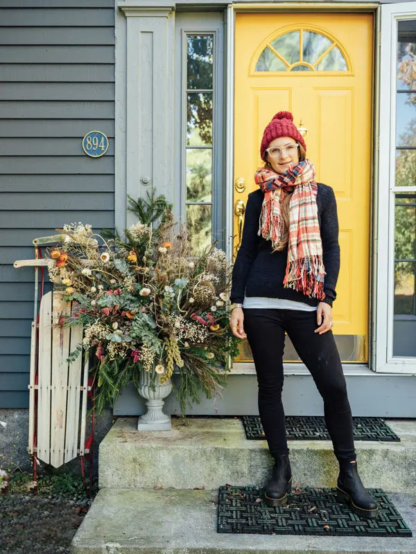 florist Anika Wilson, of Bad Rabbit Flowers, on her porch with her holiday planter arrangement