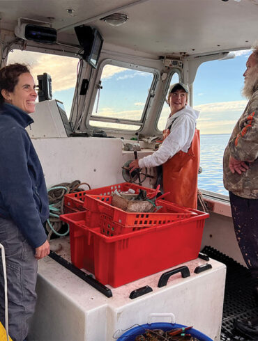 Island Institute Fellow Alumnus Jes Stevenson on a lobsterboat with two lobstermen