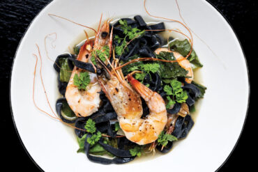 Gulf shrimp on a bed of fettuccine nero and escarole garnished with chervil sprigs