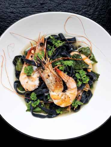 Gulf shrimp on a bed of fettuccine nero and escarole garnished with chervil sprigs