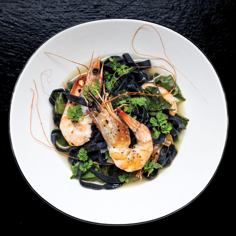 Gulf shrimp on a bed of fettuccine nero and escarole garnished with chervil sprigs