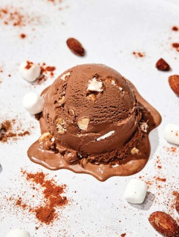 Scoop of Spicy Rocky Road ice cream surrounded with nuts and marshmallows