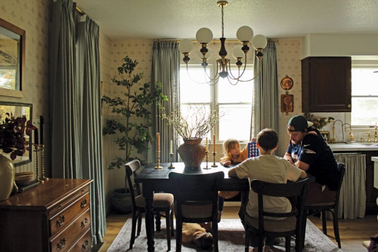 In the dining room, an espresso-colored table and secondhand chairs she stained to match provide rich counterpoints to delicate, vintage-inspired floral wallpaper, beadboard wainscoting with scalloped trim (rendered in Accessible Beige), and aqua linen curtains