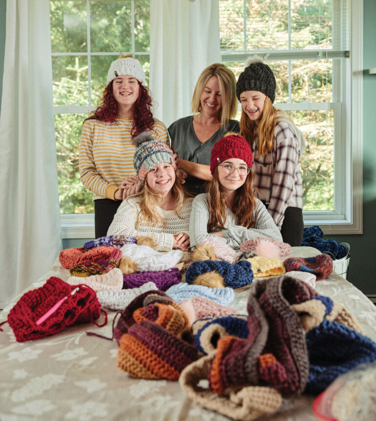 Audrey Mahlman (back row center), pictured with her daughter, Olive (seated at left), and her friends in Mahlman’s crocheted hats.