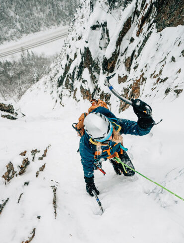 a female ice climber scaling a frozen mountain face