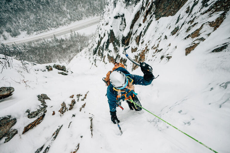 a female ice climber scaling a frozen mountain face