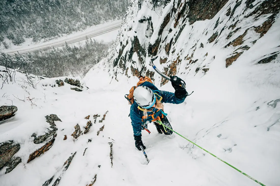 a female ice climber scaling a frozen mountain face