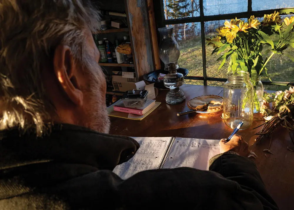 Joseph Monninger writing in a notebook from his cottage in Pembroke Maine